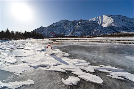 simsearch:854-02956132,k - Snowman with a red scarf and black top hat sitting on the frozen Nenana River with the Alaska Range foothills in the background, Southcentral Alaska, Winter Foto de stock - Con derechos protegidos, Código: 854-03646512