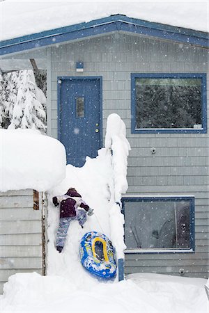 Young girl climbs the stairs of a home to sled down after a heavy snowstorm, Girdwood, Southcentral Alaska, Winter Stock Photo - Rights-Managed, Code: 854-03646607