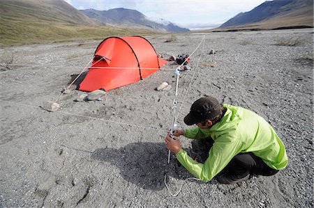 Man makes final adjustments to an electric bear fence at camp along the Hulahula River, Brooks Range, ANWR, Arctic Alaska, Summer Stock Photo - Rights-Managed, Code: 854-03740042