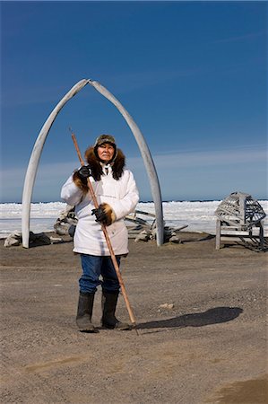 fur - Male Inupiaq Eskimo hunter wearing his Eskimo parka (Atigi), seal skin hat and wolf skin Maklak's with soles made from bearded seal skin (Ugruk) standing in front of a Bowhead whale bone arch and Umiaqs, Barrow, Arctic Alaska, Summer Stock Photo - Rights-Managed, Code: 854-03845460