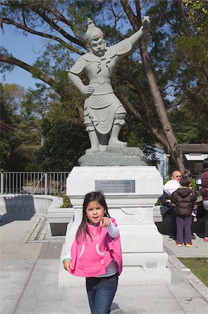 post (display for public view) - A small girl posting in front of a statue on the Approach to Po Lin Monastery, Lantau Island, Hong Kong Stock Photo - Rights-Managed, Code: 855-05984030