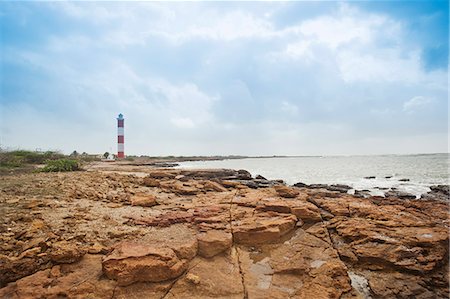 Rock formations at the coast with lighthouse in the background, Dwarka Beach, Dwarka, Gujarat, India Foto de stock - Con derechos protegidos, Código: 857-06721695