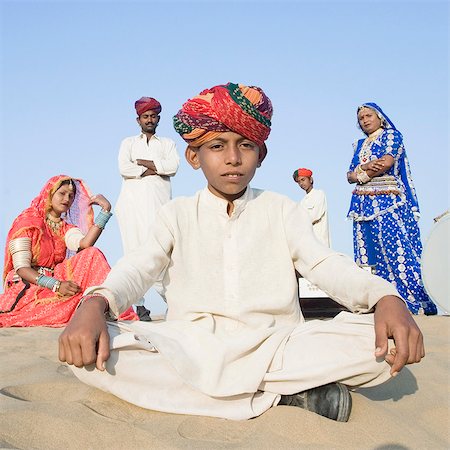 Portrait d'un garçon assis dans un désert avec quatre personnes derrière lui, le désert du Thar, Jaisalmer, Rajasthan, Inde Photographie de stock - Rights-Managed, Code: 857-03192638
