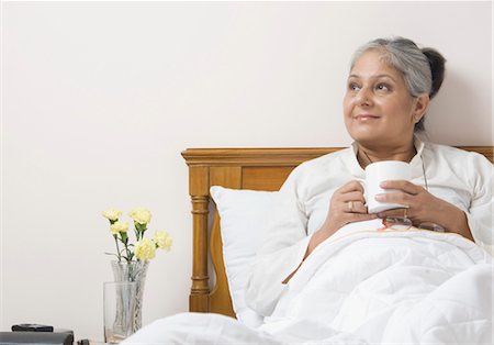 Woman holding a tea cup on the bed Stock Photo - Rights-Managed, Code: 857-03553857