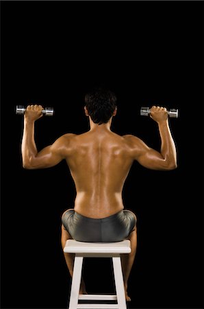Rear view of a man exercising with dumbbells Stock Photo - Rights-Managed, Code: 857-03553897