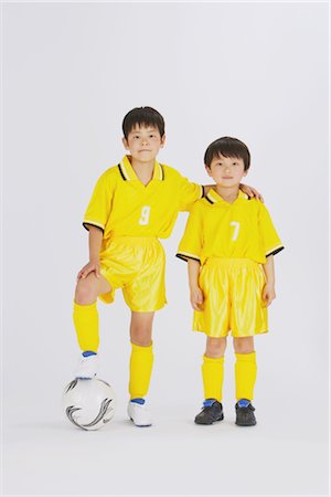 soccer player holding ball - Two brothers standing with one foot on football Stock Photo - Rights-Managed, Code: 858-03050011