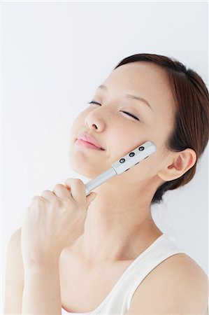 Japanese woman massaging her face with a beauty roller Stock Photo - Rights-Managed, Code: 859-06404793