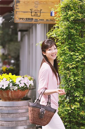 Japanese woman with her bag walking while looking at camera Stock Photo - Rights-Managed, Code: 859-06404874