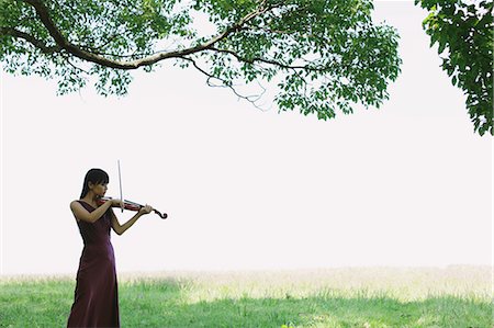 Asian woman playing the violin in a grass field Stock Photo - Rights-Managed, Code: 859-06404909