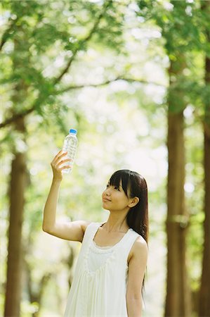 Asian woman in a white dress holding a bottle of water in the woods Stock Photo - Rights-Managed, Code: 859-06404914