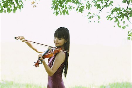 Asian woman playing the violin in a grass field Stock Photo - Rights-Managed, Code: 859-06404911