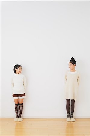 Sisters in pre-adolescent age smiling at each other in front of a white wall Stock Photo - Rights-Managed, Code: 859-06469857