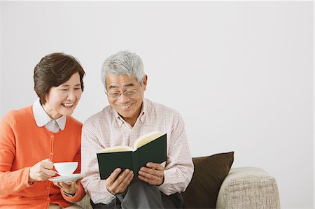 friends not men not children indoors mature joy - Senior adult couple having a coffee while reading a book on the sofa Stock Photo - Rights-Managed, Code: 859-06470191