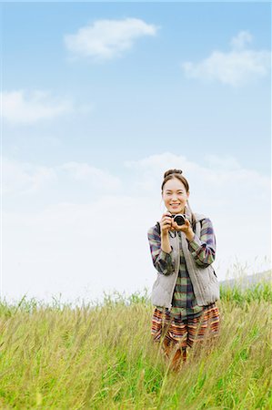 Young girl with camera smiling on grassland Foto de stock - Con derechos protegidos, Código: 859-06824600