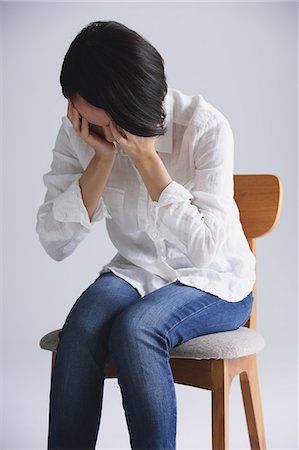 Desperate Japanese young woman in a white shirt sitting on a chair Stock Photo - Rights-Managed, Code: 859-07711139