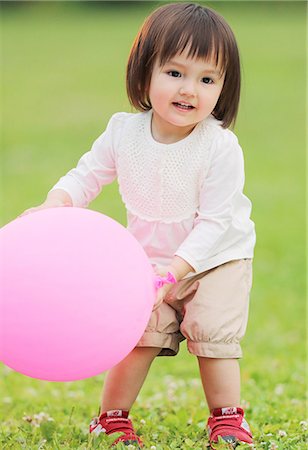 Mixed-race young girl playing with balloon at the park Foto de stock - Con derechos protegidos, Código: 859-09018848