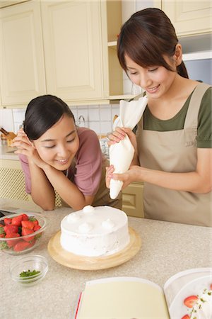 piping - Women frosting cake with icing bag Stock Photo - Rights-Managed, Code: 859-03038423