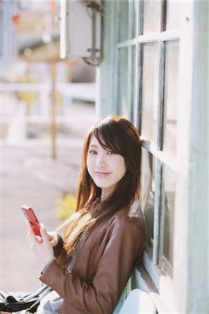 simsearch:859-03860700,k - Pretty Young Woman Holding Cellular Phone And Looking Foto de stock - Con derechos protegidos, Código: 859-03860693