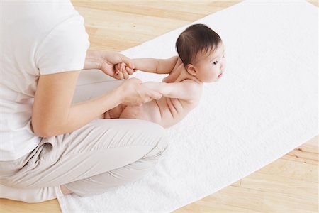 ethnic family exercise - Mother Stretching Baby's Hand While Giving Massage Stock Photo - Rights-Managed, Code: 859-03982731
