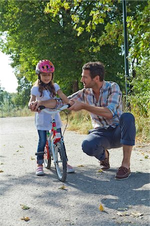 Father and daughter with helmet on bike outdoors Stock Photo - Rights-Managed, Code: 853-05840931