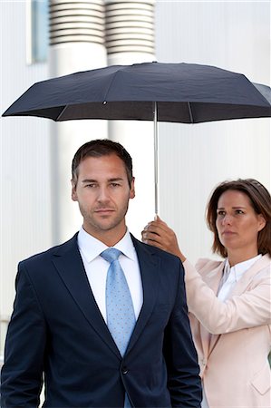 Businesswoman holding umbrella above businessman Stock Photo - Rights-Managed, Code: 853-06441696