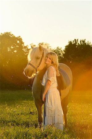 Smiling woman in white dress with horse on meadow Stock Photo - Rights-Managed, Code: 853-06442156