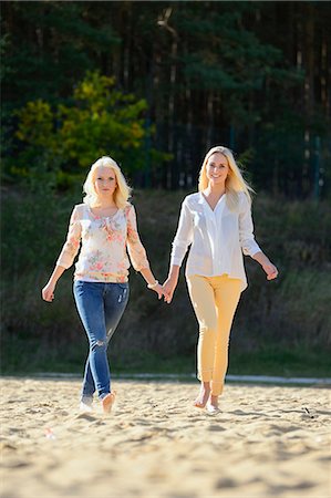 Two happy young blond women walking hand in hand on sandy beach Stock Photo - Rights-Managed, Code: 853-06442222