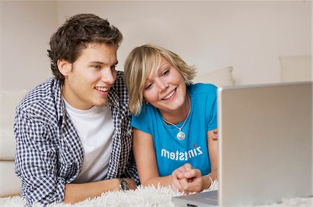 dvd - Teenager couple lying on carpet, watching media on notebook, low-angle view Stock Photo - Rights-Managed, Code: 853-03458880