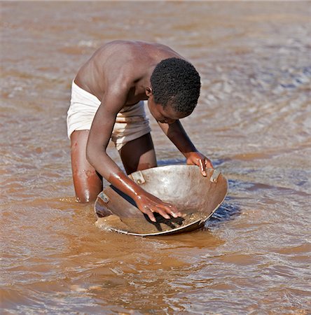 panning (for gold) - A young boy pans for alluvial gold in the Morun River near Sigor. Stock Photo - Rights-Managed, Code: 862-05998527