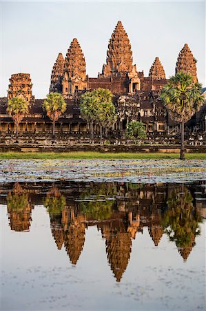 Cambodia, Angkor Wat, Siem Reap Province. The magnificent Khmer temple of Angkor Wat bathed in late afternoon sunshine with its towers reflected in a lake of red lotus flowers. Stock Photo - Rights-Managed, Code: 862-07689867