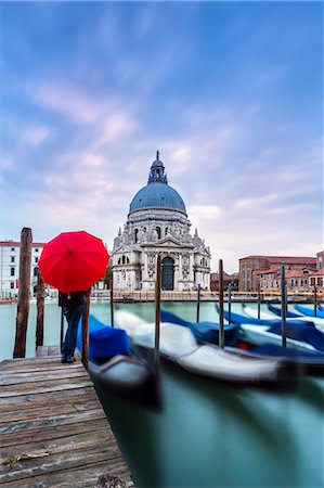 Italy, Veneto, Venice. Santa Maria della Salute church on the Grand Canal, at sunset, woman standing with red umbrella (MR) Stock Photo - Rights-Managed, Code: 862-08090393