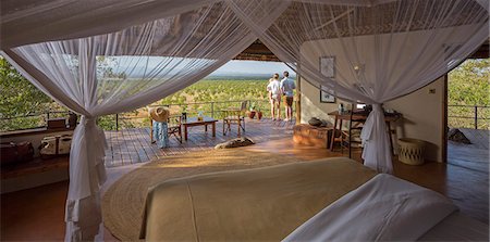 safaring - Kenya, Meru. A couple stands on the balcony of a luxury safari room overlooking Meru National Park. Photographie de stock - Rights-Managed, Code: 862-08273575