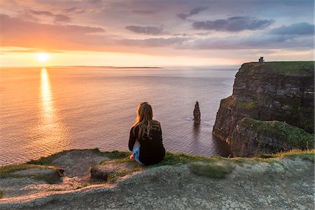 Cliffs of Moher (Aillte an Mhothair), Doolin, County Clare, Munster province, Ireland, Europe. A woman watching the sun setting from the top of the cliff. Stock Photo - Rights-Managed, Code: 862-08699399