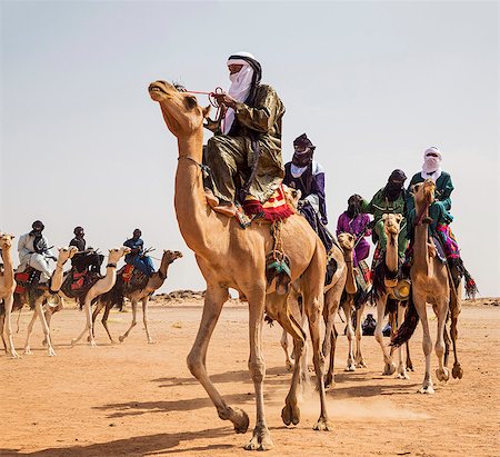 simsearch:862-03437232,k - Niger, Agadez, Dabous. A group of Tuareg men in traditional dress ride their camels across desert terrain. Stock Photo - Rights-Managed, Code: 862-08704963