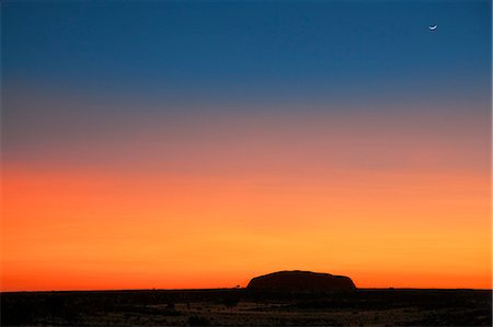 Australia,Northern Territory. Before sunrise,Uluru or Ayres Rock is silhouetted against a magnificent blood red to orange sky. This picture was taken from The Olgas,16 miles from the iconic feature. Stock Photo - Rights-Managed, Code: 862-03289181