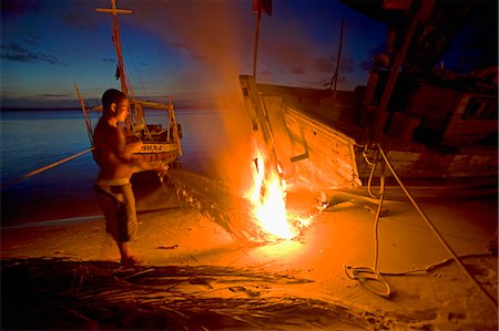 salvador - Tarring the bottom of a fishing boat during the night. The heat is used to melt and seal the tar,Tinhare archipelago in the Bahia region,north east of Brazil Stock Photo - Rights-Managed, Code: 862-03289694