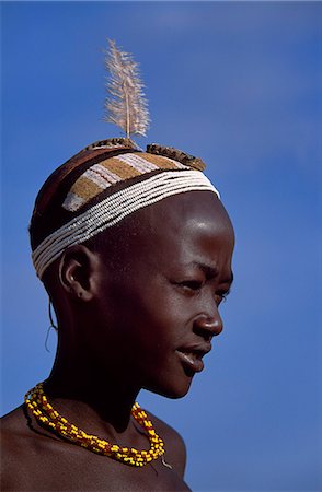 A young Dassanech boy shows off his distinctive painted clay hairdo. The central panel consists of tightly packed coils of sisal thread extracted from grain sacks that allow the scalp to breathe underneath the clay. Much the largest of the tribes in the Omo Valley numbering around 50,000,the Dassanech (also known as the Galeb,Changila or Merille) are Nilotic pastoralists and agriculturalists. Stock Photo - Rights-Managed, Code: 862-03354074