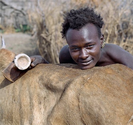 pierced ears - A Dassanech youth with his ears pierced and fitted with five brass rings. He carries a traditional wooden stool,which doubles as a pillow at night. The Dassanech speak a language of Eastern Cushitic origin. They practice animal husbandry and fishing as well as agriculture. Stock Photo - Rights-Managed, Code: 862-03354103