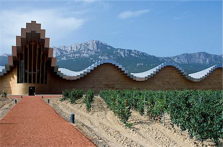 The striking architecture of Ysios winery,designed by world renowned architect Santiago Calatrava,mirrors the undulations of the limestone mountains of the Sierra de Cantabria rising behind Stock Photo - Rights-Managed, Code: 862-03354360
