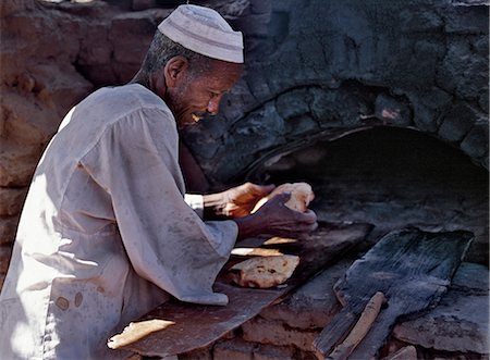sudan - A Nubian baker removes bread from his wood-fired oven. Stock Photo - Rights-Managed, Code: 862-03354582