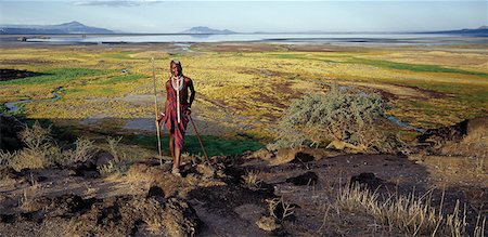 simsearch:862-03355162,k - Maasai warrior in front of Lake Natron in northern Tanzania,one of the most alkaline lakes of the Rift system. As its waters evaporate in the intense heat,sodium sesquicarbonate,known as trona or natron,solidifies to resemble giant coral heads in brightly coloured water.The pastoral Maasai graze their cattle along its southern shores where the Enkare Sero River provides welcome pasture. Foto de stock - Con derechos protegidos, Código: 862-03355160