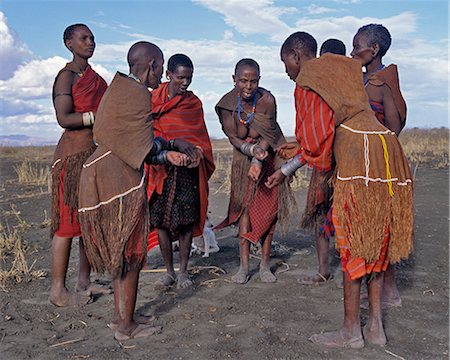 Old Datoga women wearing beautifully tanned and decorated leather dresses sing a short distance from their homes. They keep rhythm by rubbing their numerous iron bracelets together.The Datoga (known to their Maasai neighbours as the Mang'ati and to the Iraqw as Babaraig) live in northern Tanzania and are primarily pastoralists. Stock Photo - Rights-Managed, Code: 862-03355205