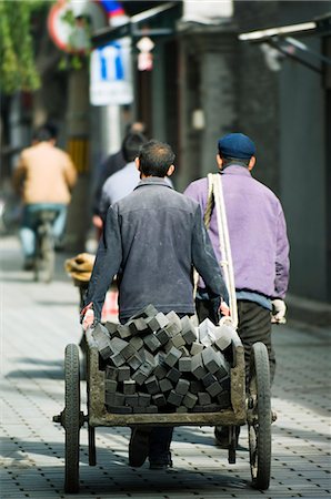 Chine, Beijing. Hommes transportant des briques de charbon de bois dans un quartier Hutong. Photographie de stock - Rights-Managed, Code: 862-03351339