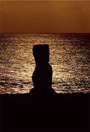 simsearch:862-03360742,k - Chile,Easter Island,Tahai. At Ahu Kote Riku,a single well preserved moai is silhouetted at sunset as it sits on top of one of the three ahus or platforms of the ceremonial centre of Tahai. Tahai is just a short walk from Easter Island's main settlement,Hanga Roa on the west coast of the island,backed by the Pacific Ocean. Stock Photo - Rights-Managed, Code: 862-03352163