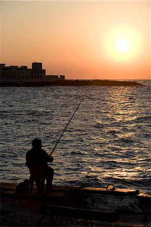 A fisherman watches as the sun goes down on the waterfront of Alexandria,Egypt Foto de stock - Con derechos protegidos, Código: 862-03352866