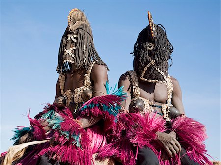 simsearch:400-06099430,k - Mali,Dogon Country,Tereli. Masked stilt dancers wearing coconut shells as breasts rest on a high wall at the Dogon village of Tereli. Tereli is situated among rocks at the base of the spectacular 120-mile-long Bandiagara escarpment. The mask dance is staged at funeral ceremonies to appease the dead and speed them on their way to the ancestral world. Stock Photo - Rights-Managed, Code: 862-03364207