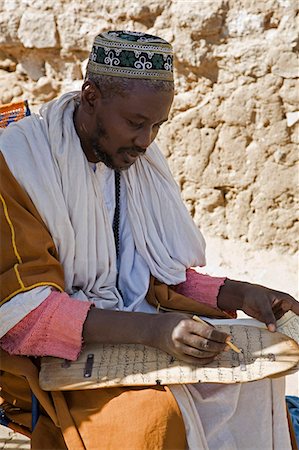 simsearch:862-03437232,k - Mali,Timbuktu. An Islamic teacher corrects a child's homework on a wooden 'slate' in Timbuktu. Since ancient times,Timbuktu has been a place of Islamic learning. There are numerous madrasa there to this day. Stock Photo - Rights-Managed, Code: 862-03364240