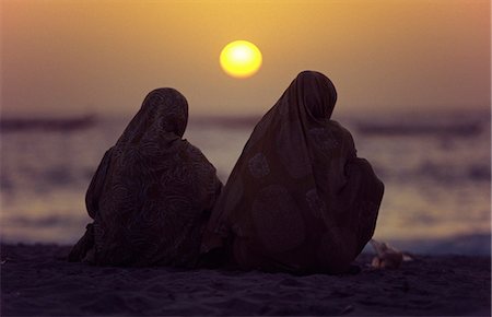 Mauritanian women shrouded in melafas are silhouetted against the afternoon sun at the Plage des Pecheurs (Fishermens Beach) near Nouakchott. Stock Photo - Rights-Managed, Code: 862-03364311