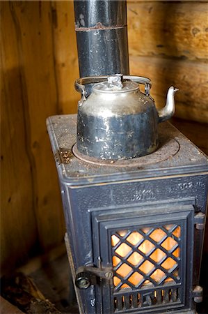 Norway,Troms,Lyngen Alps. A traditional wooden cabin high in the mountains provides an 'open' source of accommadation where a wood burning stove heats a kettle of water. Foto de stock - Con derechos protegidos, Código: 862-03365586