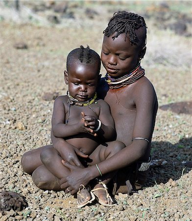 Childhood is brief in nomadic communities. From an early age,Turkana girls help their mothers with the household chores and look after their younger brothers and sisters during the day. The baby has wooden charms round her neck to ward off evil spirits. Stock Photo - Rights-Managed, Code: 862-03366121